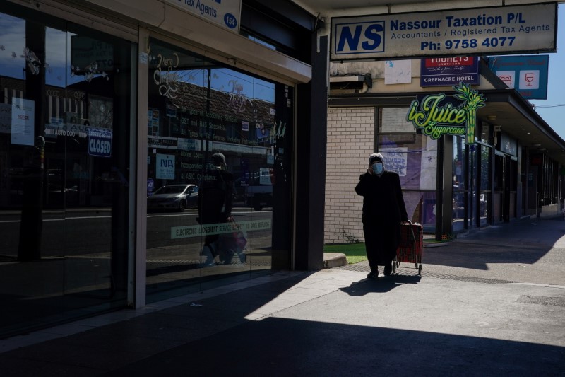 &copy; Reuters. FILE PHOTO: A woman wearing a protective face mask pulls a shopping trolley down the sidewalk during a lockdown to curb the spread of a coronavirus disease (COVID-19) outbreak in the Canterbury-Bankstown local government area of southwest Sydney, Australi