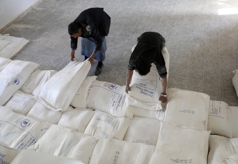 &copy; Reuters. عمال ينقلون أجولة دقيق في مركز لتوزيع المساعدت في صنعاء يوم 26 يناير كانون الثاني 2021. رويترز