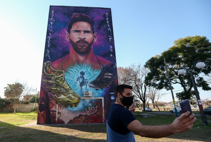 &copy; Reuters. شاب يلتقط صورة سيلفي مع لوحة كبيرة للاعب ليونيل ميسي قرب المنزل الذي نشأه فيه في الأرجنتين. رويترز