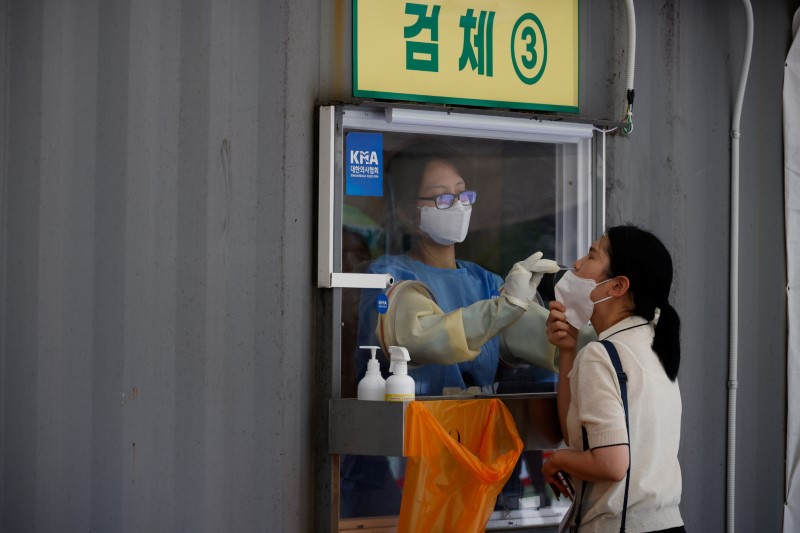 &copy; Reuters. 韓国の保健福祉相は１１日、新型コロナウイルスの新規感染者が２２００人を超え、過去最多を記録したと明らかにした。写真は今年７月、新型コロナウイルスの検査を受ける女性。ソウル