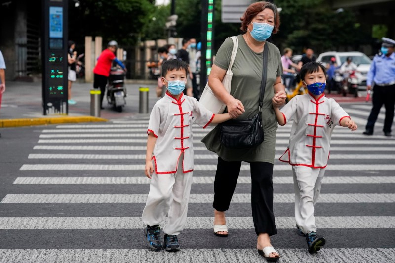 &copy; Reuters. 中国では、足元の新型コロナウイルス感染拡大が４週目に入る中、警戒態勢が維持されている。写真は、マスク着用で通行する上海の人々。２０２１年８月１０日に撮影。（２０２１年　ロ