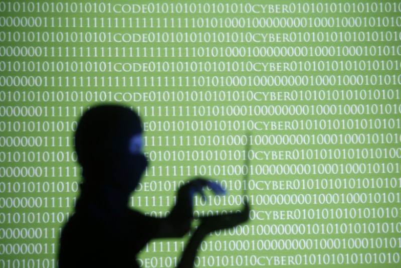 &copy; Reuters. FILE PHOTO:   A person wearing a balaclava is silhouetted as he poses with a laptop in front of a screen projected with the word 'cyber' and binary code, in this picture illustration taken in Zenica October 29, 2014.     REUTERS/Dado Ruvic/File photo
