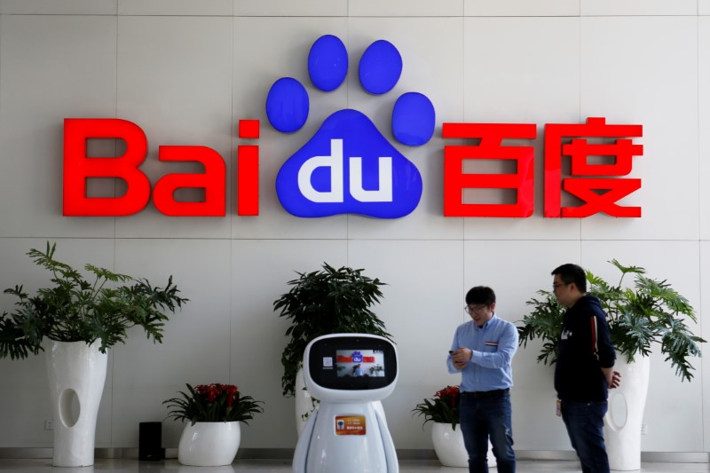 © Reuters. FILE PHOTO: Men interact with a Baidu AI robot near the company logo at its headquarters in Beijing, China April 23, 2021. REUTERS/Florence Lo/File Photo