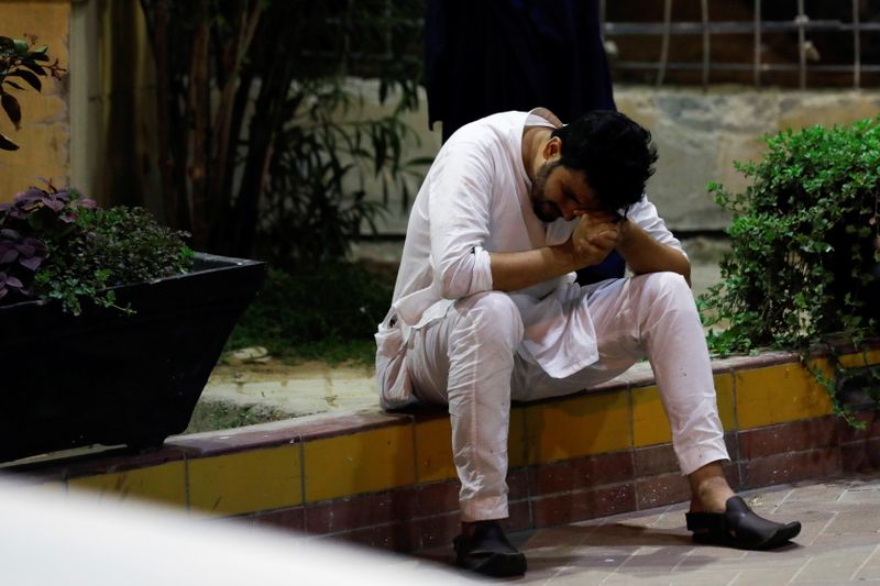 © Reuters. أحد أقارب القتلى الذين قتلوا في هجوم بقنبلة يدوية أثناء عودتهم من حفل زفاف يجلس  عند مستشفى في كراتشي يوم الأحد. تصوير: أخطر سومرو - رويترز