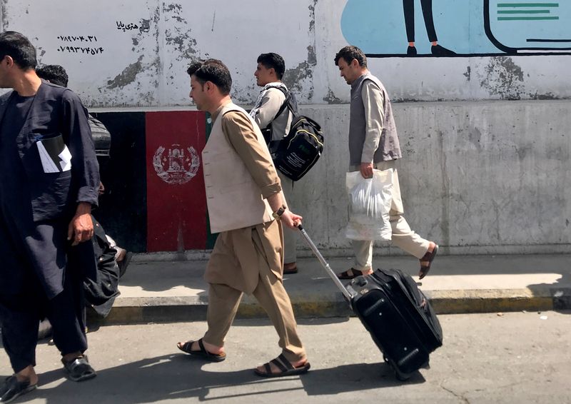 © Reuters. مسافرون أفغان يسيرون باتجاه المطار في كابول يوم الأحد - رويترز