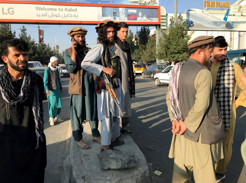 &copy; Reuters. أعضاء من حركمة طالبان يقفون خارج مطار حامد كرزاي في كابول يوم الاثنين - رويترز.
