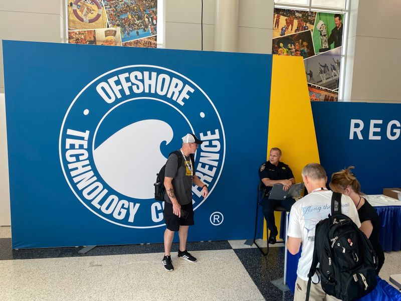 © Reuters. People stand next to a logo at the Offshore Technology Conference in Houston, Texas, U.S., August 14, 2021. Picture taken August 14, 2021. REUTERS/Gary McWilliams