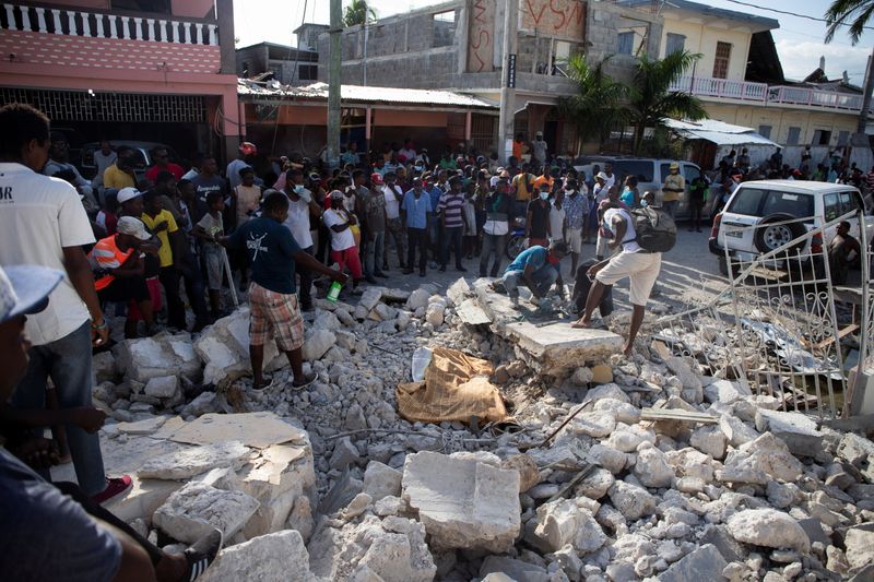 &copy; Reuters. Pessoas olham o corpo de uma pessoa nos escombros depois de um terremoto em Les Cayes, no Haiti
15/08/2021 REUTERS/Estailove St-Val