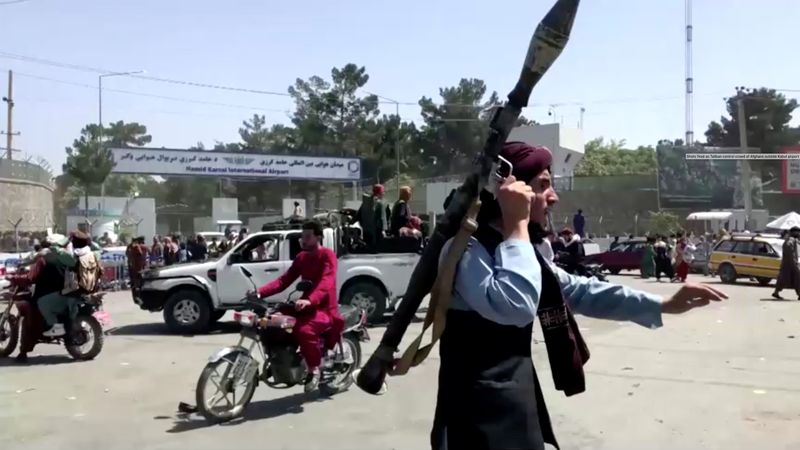 © Reuters. مسلح من طالبان يسرع نحو حشد خارج مطار كابول يوم الاثنين في صورة مأخوذة من مقطع مصور لتلفزيون رويترز.
