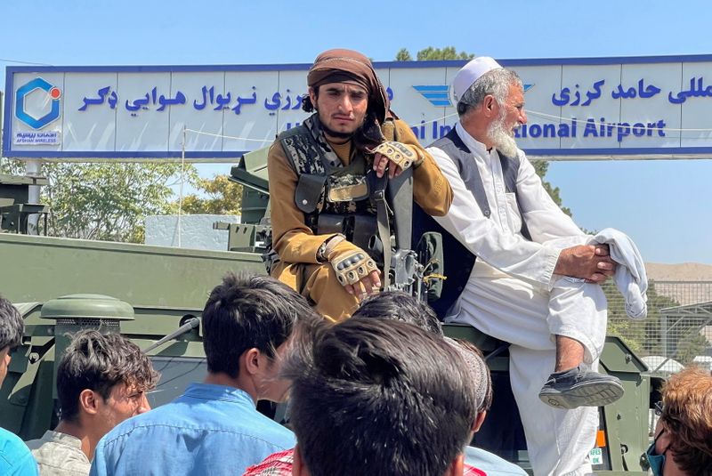 &copy; Reuters. مقاتل من طالبان (يسارا) يجلس فوق عربة مصفحة خارج مطار حامد كرزاي الدولي في كابول يوم الاثنين. صورة لرويترز. تحظر إعادة بيع الصورة أو حفظها في 