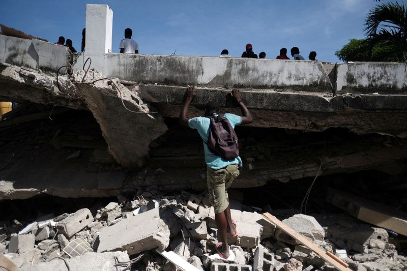 &copy; Reuters. Un hombre busca en el sitio de un hotel derrumbado después del terremoto de magnitud 7,2 del sábado, en Les Cayes, Haití. 16 de agosto de 2021. REUTERS/Ricardo Arduengo 