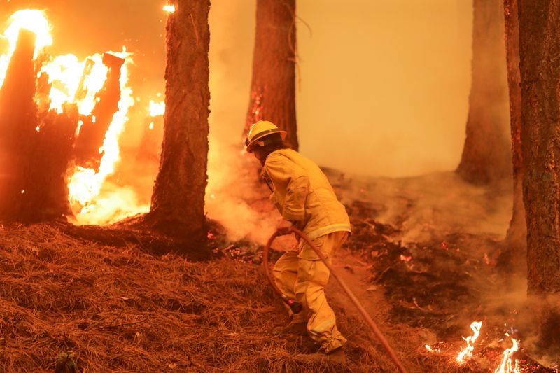 &copy; Reuters. FILE PHOTO: A firefighter continues to hold the line of the Dixie Fire near Taylorsville, California, U.S., August 10, 2021. REUTERS/David Swanson