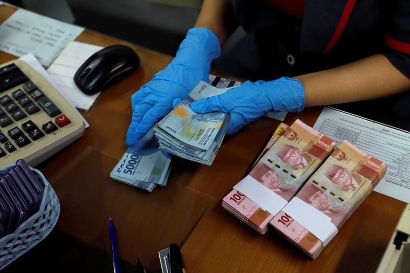 &copy; Reuters. FILE PHOTO:  An employee wearing a face mask and synthetic gloves counts Indonesia's rupiah banknotes at a currency exchange office amid the spread of coronavirus disease (COVID-19) in Jakarta, Indonesia, March 19, 2020. REUTERS/Willy Kurniawan/File photo
