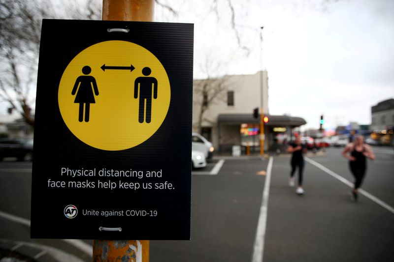 &copy; Reuters. FOTO DE ARCHIVO: Gente corriendo junto a un cartel de distanciamiento social en el primer día de la nueva medida de seguridad contra la enfermedad del coronavirus (COVID-19) de Nueva Zelanda que obliga a llevar una máscarilla en el transporte público, 