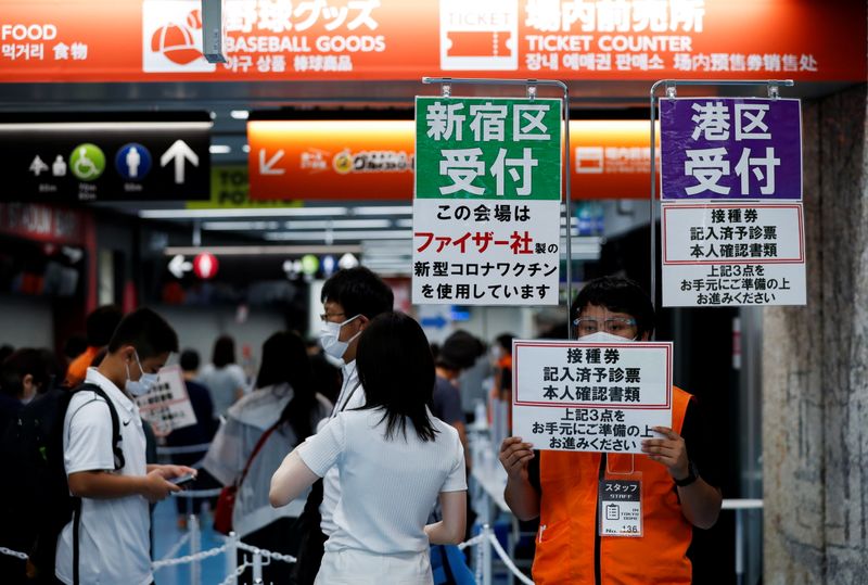 &copy; Reuters. Delle persone con indosso la mascherina ricevono indicazioni presso il Tokyo Dome, utilizzato come centro per le vaccinazioni a Tokyo, Giappone, 16 agosto 2021 REUTERS/Issei Kato