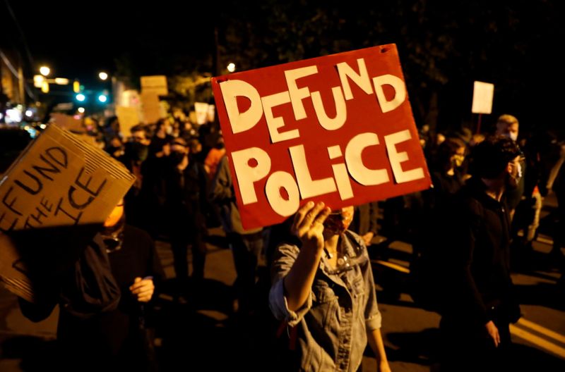 &copy; Reuters. FILE PHOTO: Demonstrators hold a sign reading "Defund the police" during a protest over the death of a Black man, Daniel Prude, after police put a spit hood over his head during an arrest on March 23, in Rochester, New York, U.S. September 6, 2020. REUTER