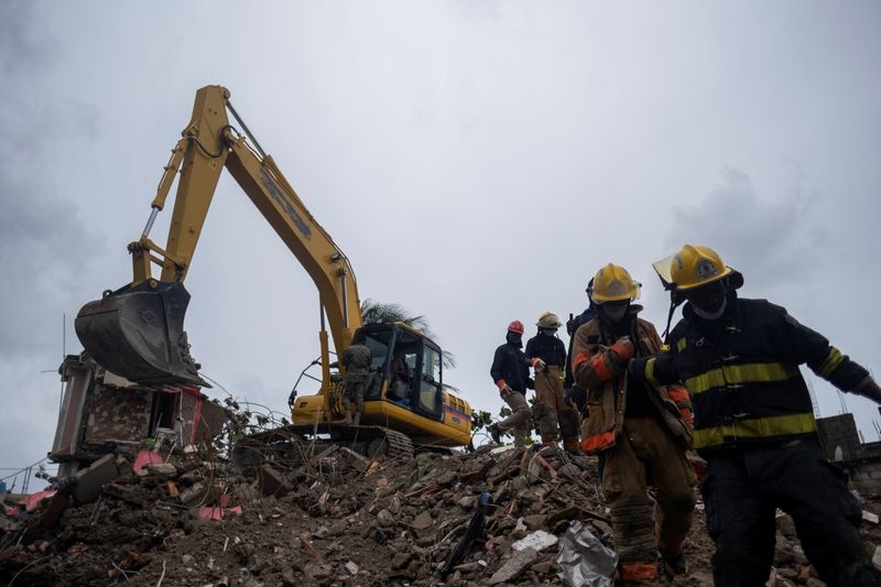 © Reuters. Haitian firefighters search for survivors under the rubble of a destroyed building after Saturday's 7.2 magnitude quake, in Les Cayes, Haiti August 17, 2021. REUTERS/Ricardo Arduengo