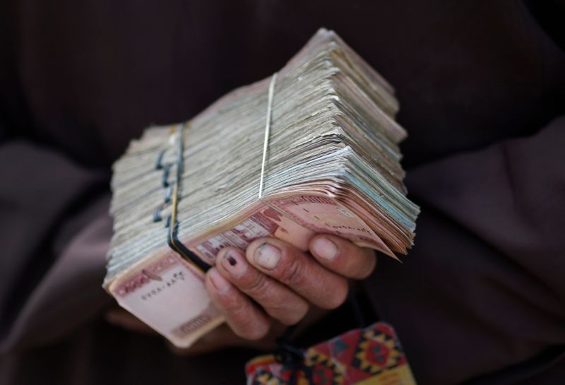 &copy; Reuters. FOTO DE ARCHIVO; Un cambista sostiene una pila de moneda afgana en una calle del centro de Kabul, 2 de abril de 2014. REUTERS/Tim Wimborne