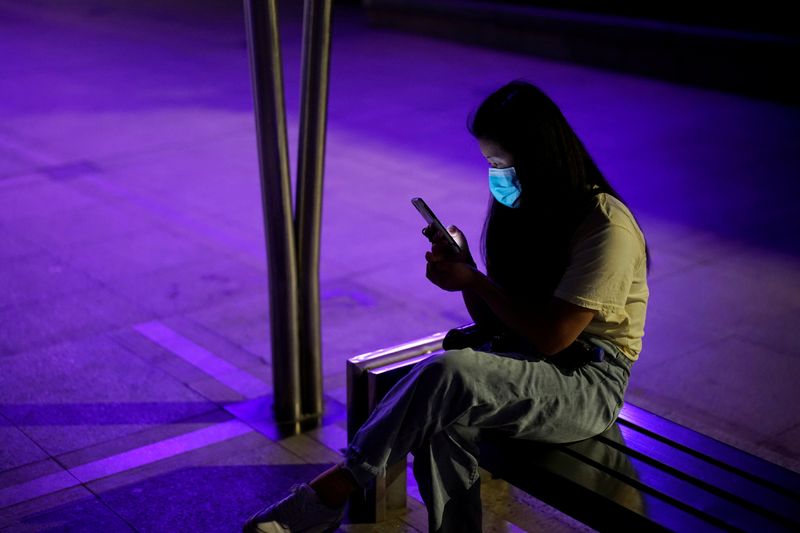 &copy; Reuters. FILE PHOTO: A woman wearing a protective face mask uses a phone at a park in Wuhan, the Chinese city hit the hardest by the coronavirus disease (COVID-19) outbreak, in the Hubei province, China, May 15, 2020. REUTERS/Aly Song