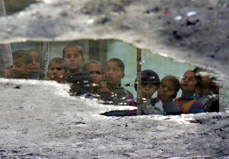 &copy; Reuters. أيتام في كابول تنعكس وجوههم على صفحة بركة ماء. تصوير: أحمد مسعود - رويترز