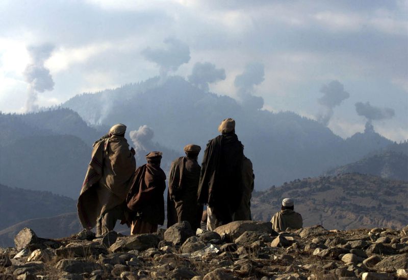 © Reuters. FILE PHOTO: Anti-Taliban Afghan fighters watch several explosions from U.S. bombings in the Tora Bora mountains in Afghanistan in the hunt for al Qaeda fighters, December 16, 2001./File Photo