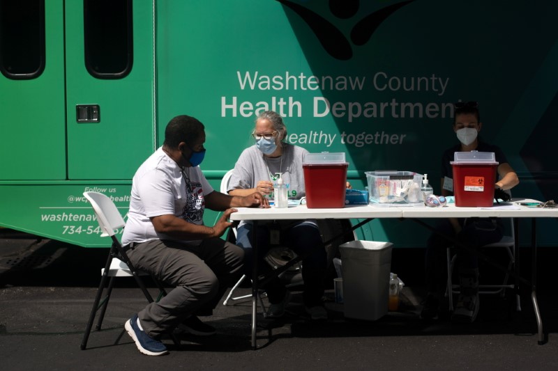 &copy; Reuters. FILE PHOTO: Jane Nickert, director of nursing for the Washtenaw County Health Department converses with a person getting ready to receive their COVID-19 vaccine during an event hosted by Southeast Michigan Pull Over Prevention at Grace Fellowship Church i