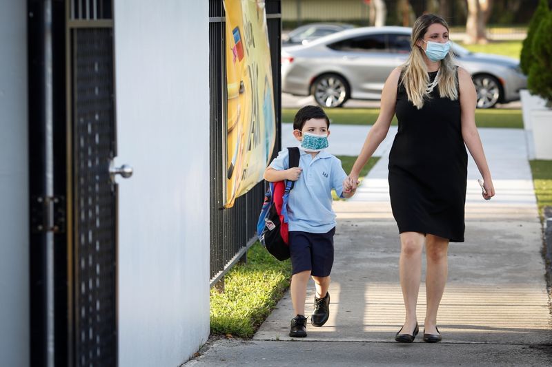 &copy; Reuters. FILE PHOTO: A teacher walks with a student, as they wear protective masks on the first day of school, amid the coronavirus disease (COVID-19) pandemic, at St. Lawrence Catholic School in North Miami Beach, Florida, U.S. August 18, 2021. REUTERS/Marco Bell