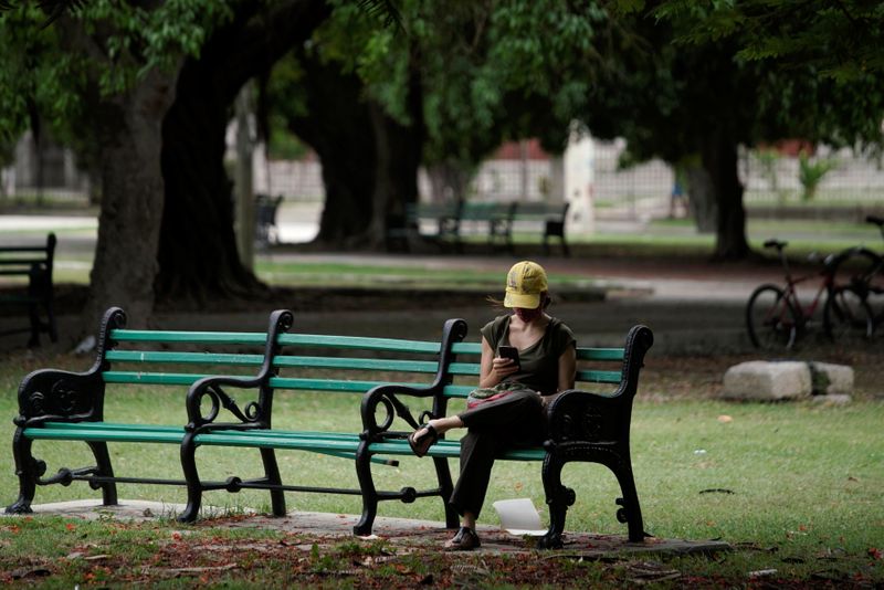 © Reuters. A woman connects to the internet at a hotspot in a public park in Havana, Cuba, August 18, 2021. REUTERS/Alexandre Meneghini