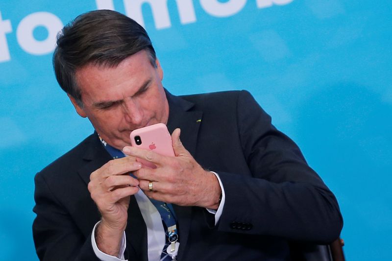 &copy; Reuters. Presidente Jair Bolsonaro mexe em telefone celular durante cerimônia no Palácio do Planalto
20/08/2019 REUTERS/Adriano Machado