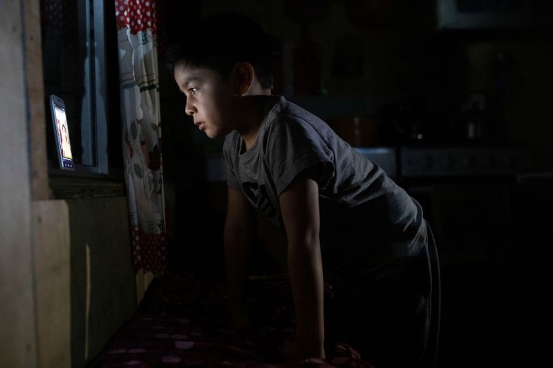 &copy; Reuters. Diego Guerrero, de 7 años, observa un video en un teléfono móvil gracias a una débil señal que recibe en la localidad de Sotomó, en el extremo sur de Chile. REUTERS/Pablo Sanhueza        