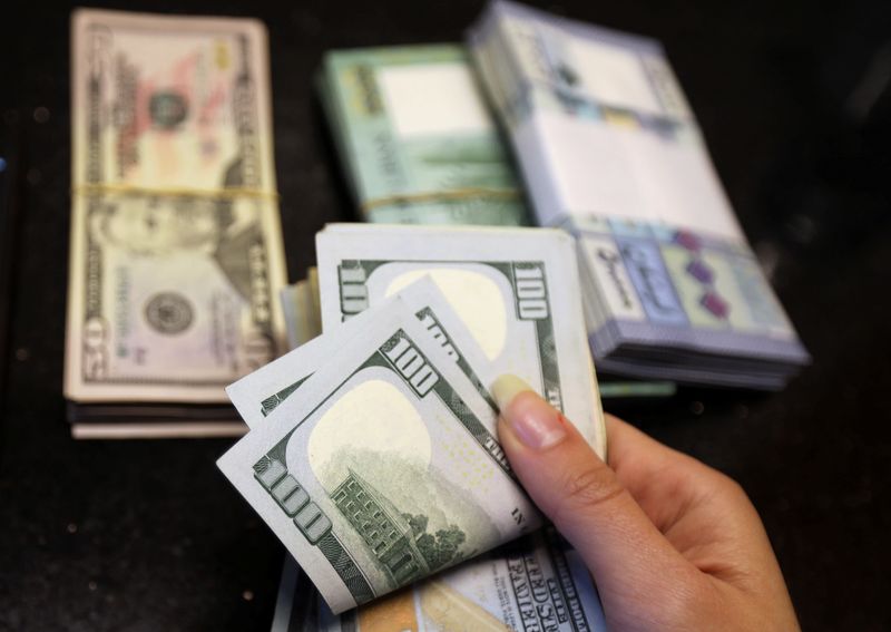 &copy; Reuters. A woman counts U.S. dollar banknotes as Lebanese pounds are pictured in the background at a currency exchange shop in Beirut, Lebanon April 3, 2020.  REUTERS/Mohamed Azakir