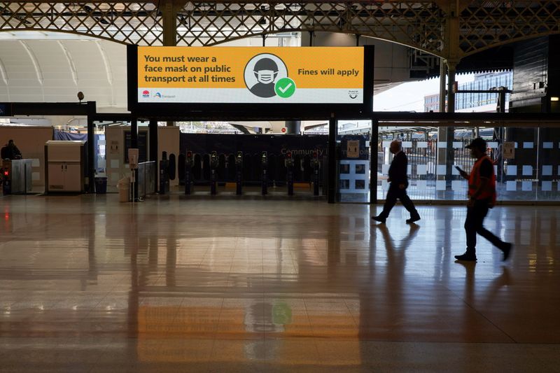 © Reuters. People walk past a public health message regarding the wearing of masks on public transport, at the quiet Central Station during a COVID-19 lockdown in Sydney, Australia, August 20, 2021.  REUTERS/Loren Elliott