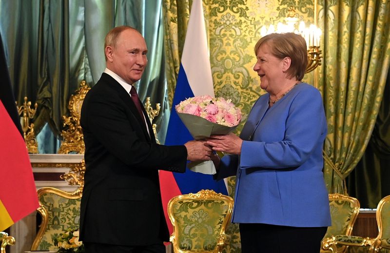 © Reuters. Russian President Vladimir Putin presents flowers to German Chancellor Angela Merkel during their meeting at the Kremlin in Moscow, Russia August 20, 2021. Sputnik/Kremlin via REUTERS ATTENTION EDITORS - THIS IMAGE WAS PROVIDED BY A THIRD PARTY.