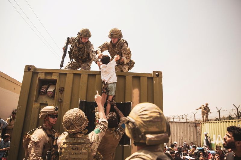 © Reuters. جنود بريطانيون وأتراك من قوات التحالف وآخرون من مشاة البحرية الأمريكية يساعدون في عمليات الإجلاء بمطار حامد كرزاي الدولي في كابول يوم الجمعة في صورة من مشاة البحرية الأمريكية. حصلت رويترز على الصورة من طرف ثالث.