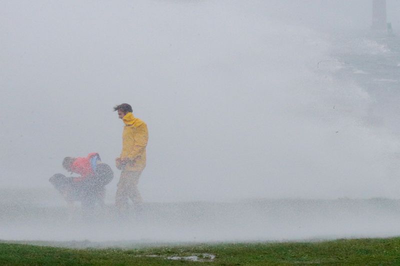 © Reuters. People and a dog are sprayed with wind driven water off the waves at Fort Adams State Park as Tropical Storm Henri makes landfall in Newport, Rhode Island, U.S., August 22, 2021.   REUTERS/Brian Snyder