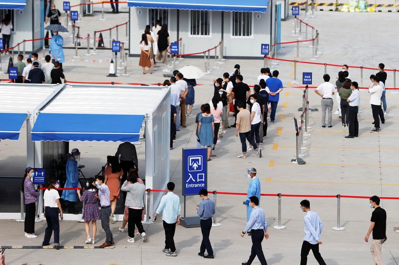 © Reuters. Diversi membri dello staff dell'aeroporto internazionale di Shanghai Pudong in linea per sottoporsi a test di massa contro il Covid-19, a Shanghai.  cnsphoto via REUTERS