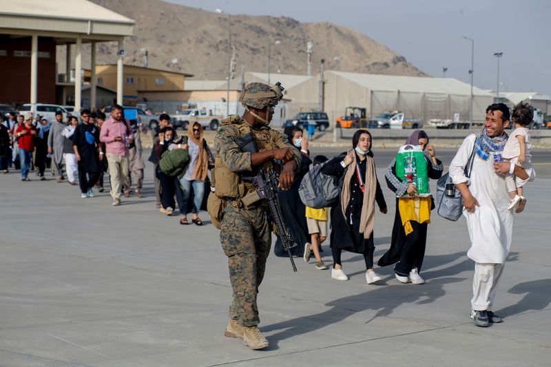 &copy; Reuters. A U.S. Marine assigned to 24th Marine Expeditionary Unit escorts evacuees during an evacuation at Hamid Karzai International Airport, Afghanistan, in this photo taken on August 18, 2021 and released by U.S. Navy on August 20, 2021. U.S NAVY/Central Comman