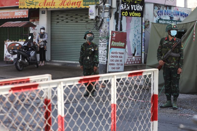 &copy; Reuters. ベトナム政府は２３日、新型コロナウイルス流行の震源地となっている最大都市ホーチミン市で厳格なロックダウン（都市封鎖）を実施するため、軍隊を派遣した。軍のチェックポイントで