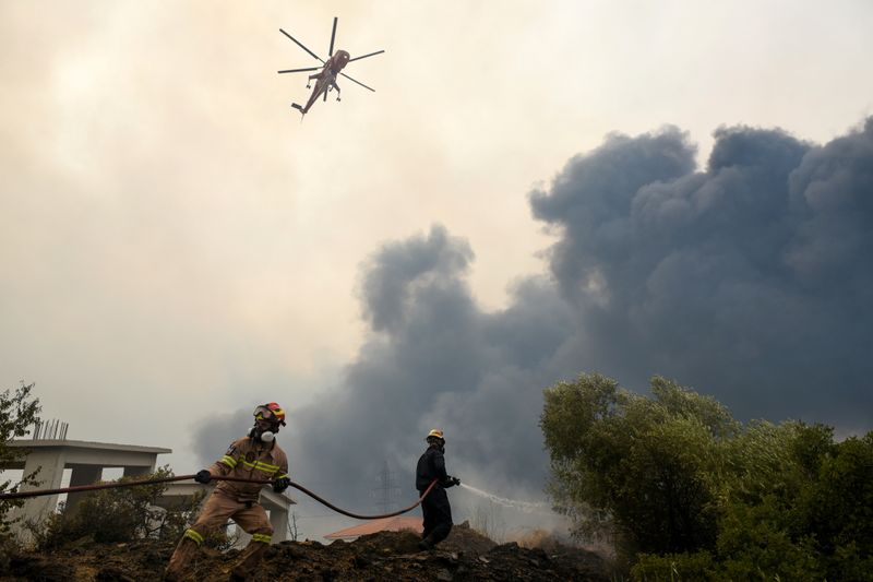 &copy; Reuters. اثنان من رجال الإطفاء أثناء مكافحة حريق غابات بالقرب من قرية افيدنيس شمال أثينا يوم السادس من أغسطس اب 2021. تصوير رويترز. 