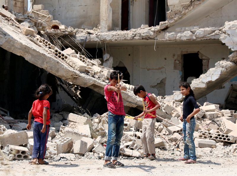 © Reuters. صورة من أرشيف رويترز لأطفال يلعبون وسط أطلال مبنى في مدينة درعا  السورية.