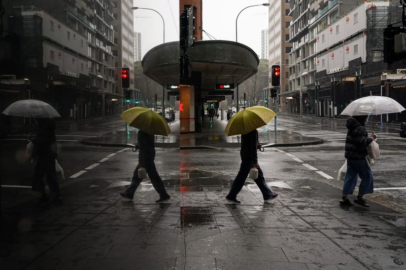 © Reuters. People with umbrellas walk through the quiet city centre during a lockdown to curb the spread of a coronavirus disease (COVID-19) outbreak in Sydney, Australia, August 24, 2021.  REUTERS/Loren Elliott