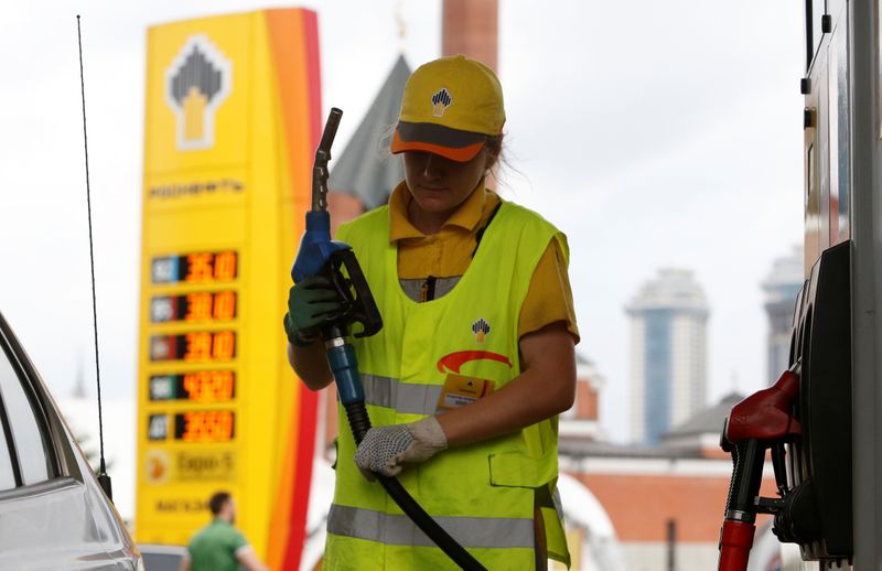 © Reuters. An employee holds a fuel nozzle at a Rosneft petrol station, with a mosque seen in the background, in Moscow, Russia, July 4, 2016. REUTERS/Sergei Karpukhin