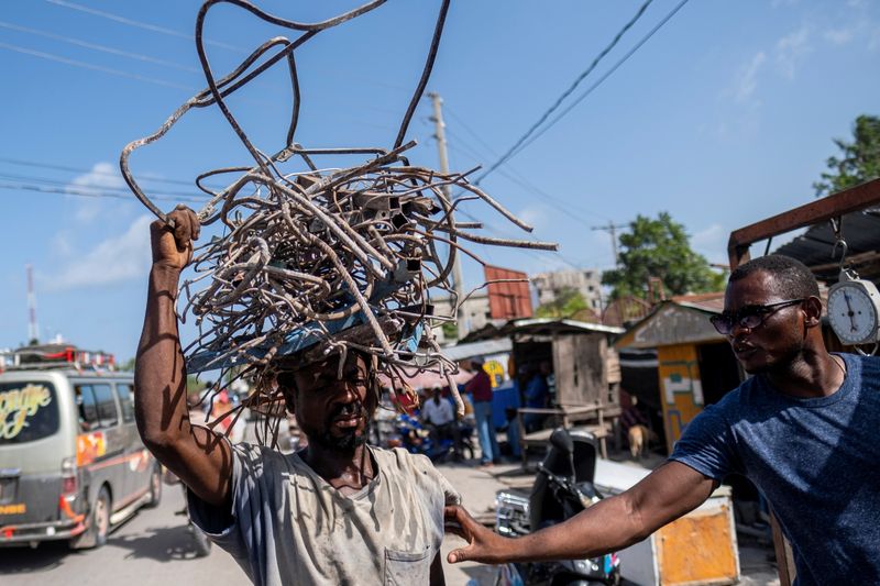&copy; Reuters. Imagen de archivo de un reciclador ofreciendo comprar metal a un hombre que transporta sobre su cabeza una pila de metal retirado desde casas destruidas por el terremoto de magnitud 7,2 en Les Cayes, Haití. 21 de agosto, 2021. REUTERS/Ricardo Arduengo/Ar