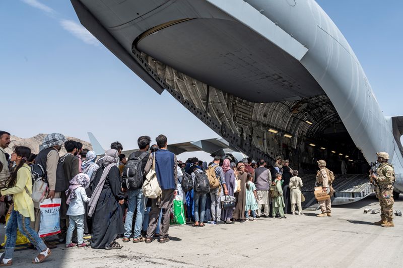 &copy; Reuters. Afegãos embarcam para deixar o país no aeroporto Hamid Karzai. 21/8/2021. Air Force/Senior Airman Brennen Lege/Handout via REUTERS 