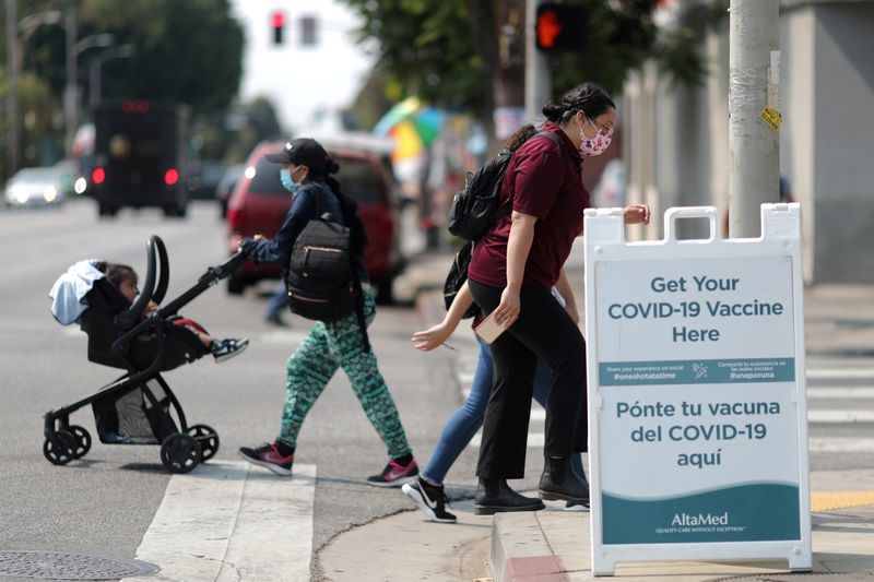 © Reuters. FOTO DE ARCHIVO: Personas caminan frente a un cartel de un centro de vacunación de coronavirus (COVID-19) en Los Angeles, California, EEUU, 17 agosto del 2021. REUTERS/Lucy Nicholson/Foto de Archivo