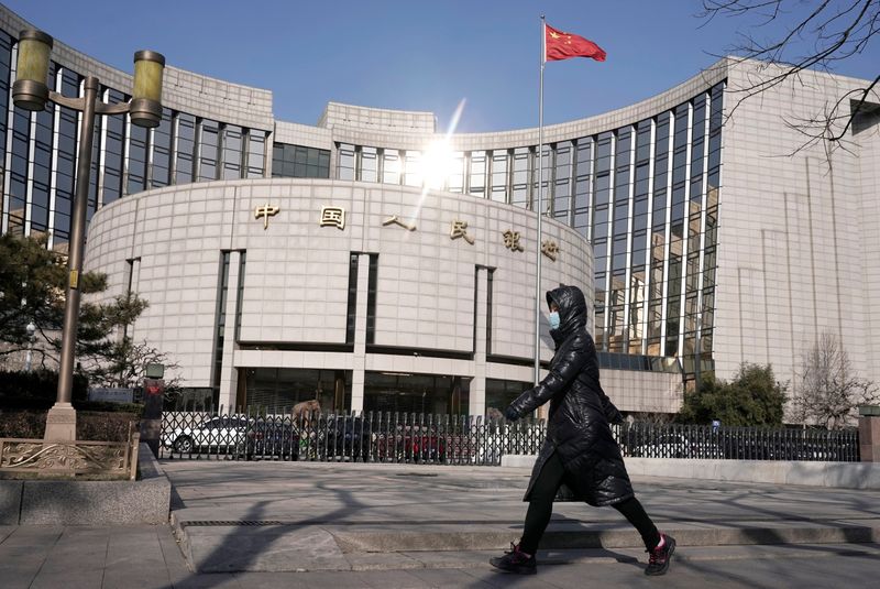 &copy; Reuters. FOTO DE ARCHIVO: Una mujer con mascarilla pasa por delante de la sede del Banco Popular de China, el banco central, en Pekín, China, mientras el país se ve afectado por un brote del nuevo coronavirus, 3 de febrero de 2020. REUTERS/Jason Lee