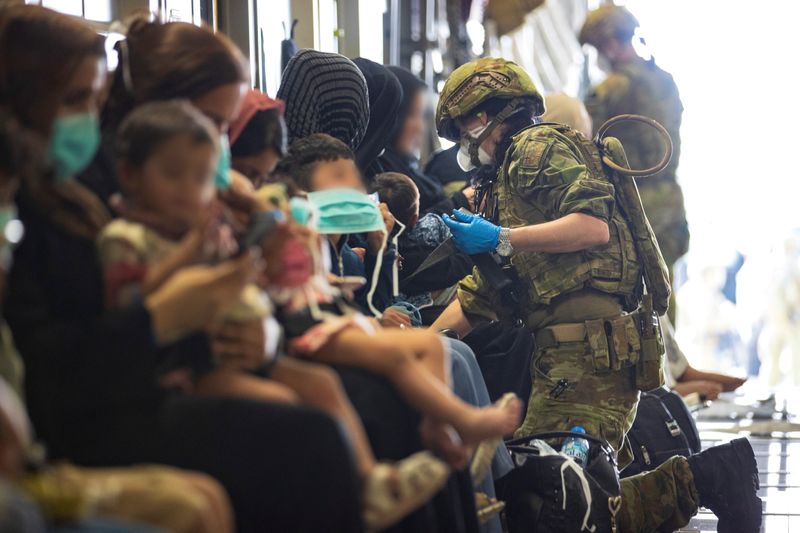 © Reuters. Il Royal Australian Air Force Air Load Team assiste gli sfollati afghani a bordo dell'aereo Royal Australian Air Force C-17A Globemaster III, prima della partenza dall'aeroporto internazionale Hamid Karzai di Kabul, Afghanistan, 22 agosto 2021. SGT Glen McCarthy/ Dipartimento australiano di Difesa/Dispensa tramite REUTERS