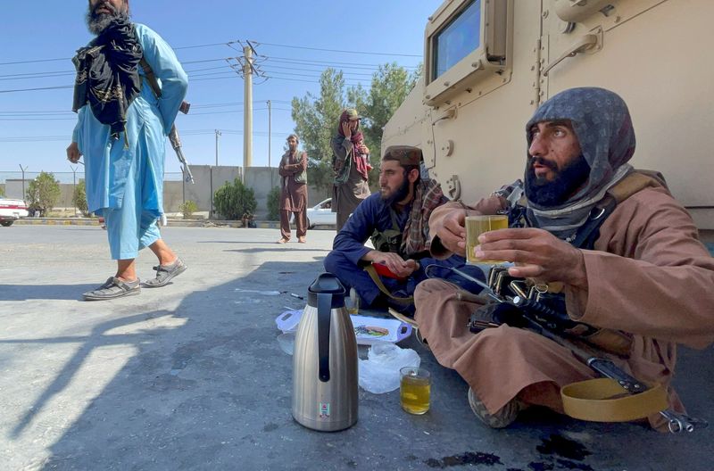 © Reuters. Armed Taliban men drink tea as Taliban forces block the roads around the airport after yesterday's explosions in Kabul, Afghanistan August 27, 2021. REUTER/Stringer 