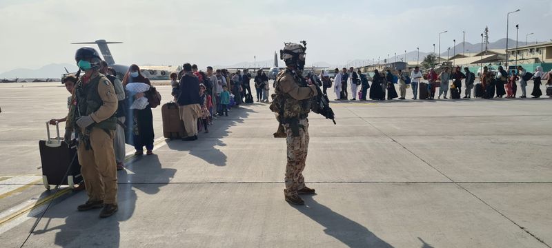 &copy; Reuters. Degli sfollati afghani fotografati mentre salgono a bordo del velivolo militare italiano  C130J. Kabul, Afghanistan, 22 agosto 2021. Italian Ministry of Defence/Handout via REUTERS