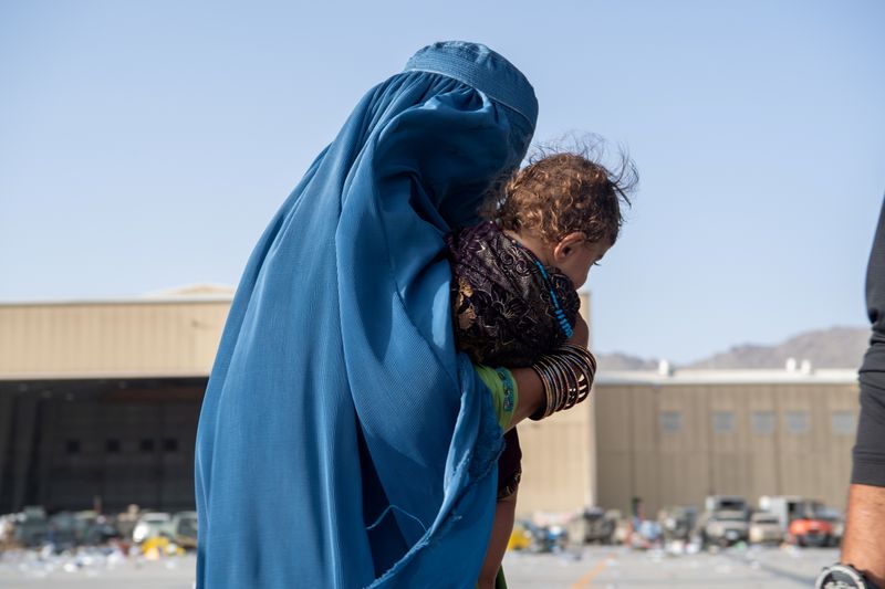 &copy; Reuters. FILE PHOTO: A woman carries a child as passengers board a U.S. Air Force C-17 Globemaster III assigned to the 816th Expeditionary Airlift Squadron in support of the Afghanistan evacuation at Hamid Karzai International Airport in Kabul, Afghanistan, August